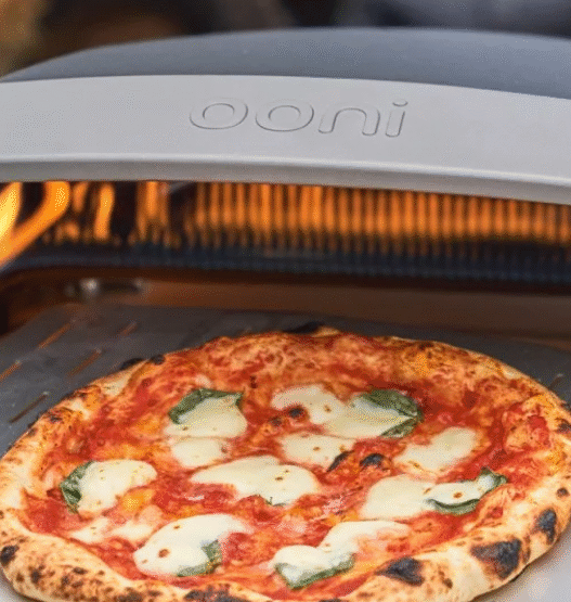 Freshly baked Neapolitan pizza on Ooni oven in backyard setting